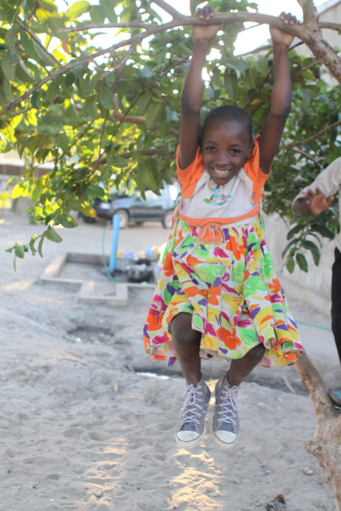 happy child in a colorful dress plays at valentine project children's home-dar es salaam, tanzania