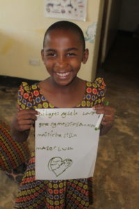 a smiling child in a colorful uniform at the valentine project children's home in dar es salaam tanzania