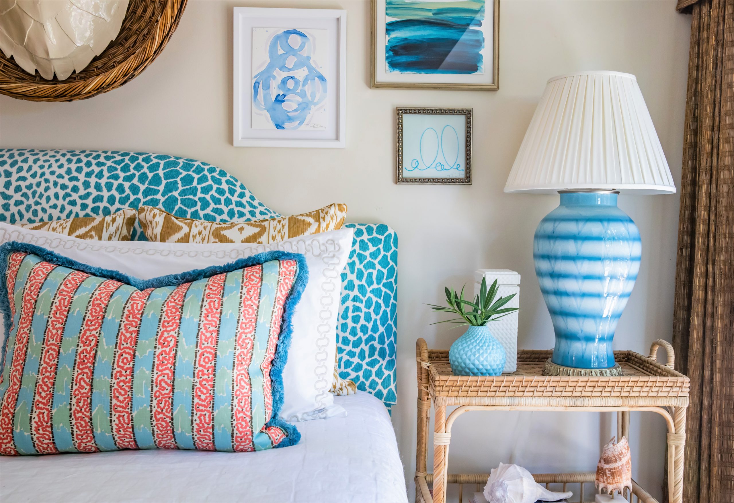 Master Bedroom with pops of color on the bed, a rattan bedside table and ceramic lamp