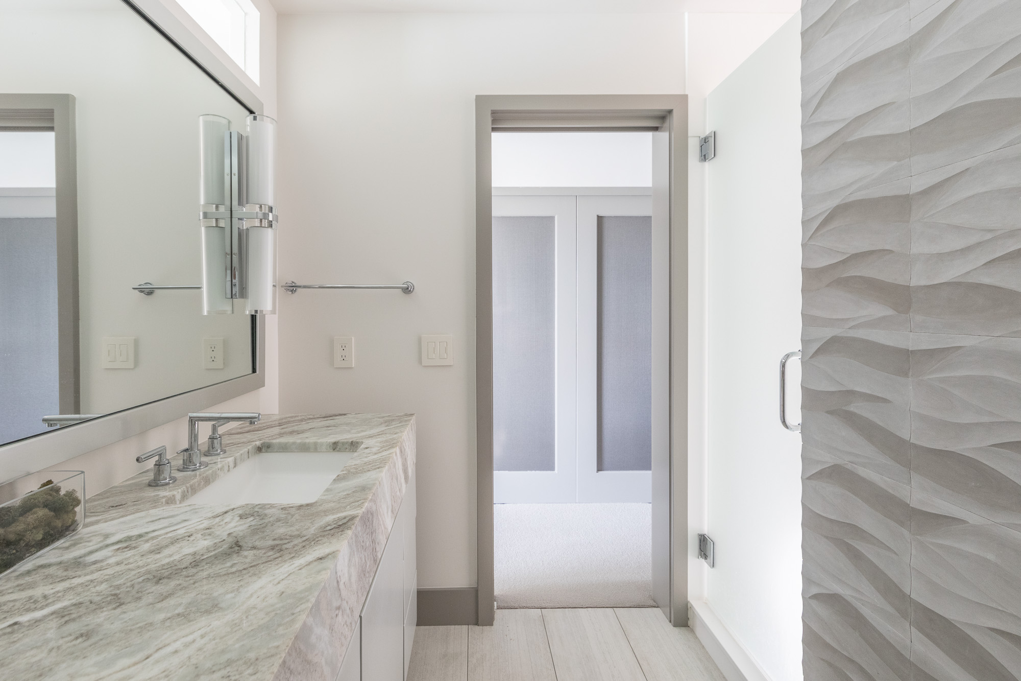 Clean-lined master bath features a wave-like pattern on shower door and marble countertops on double vanity