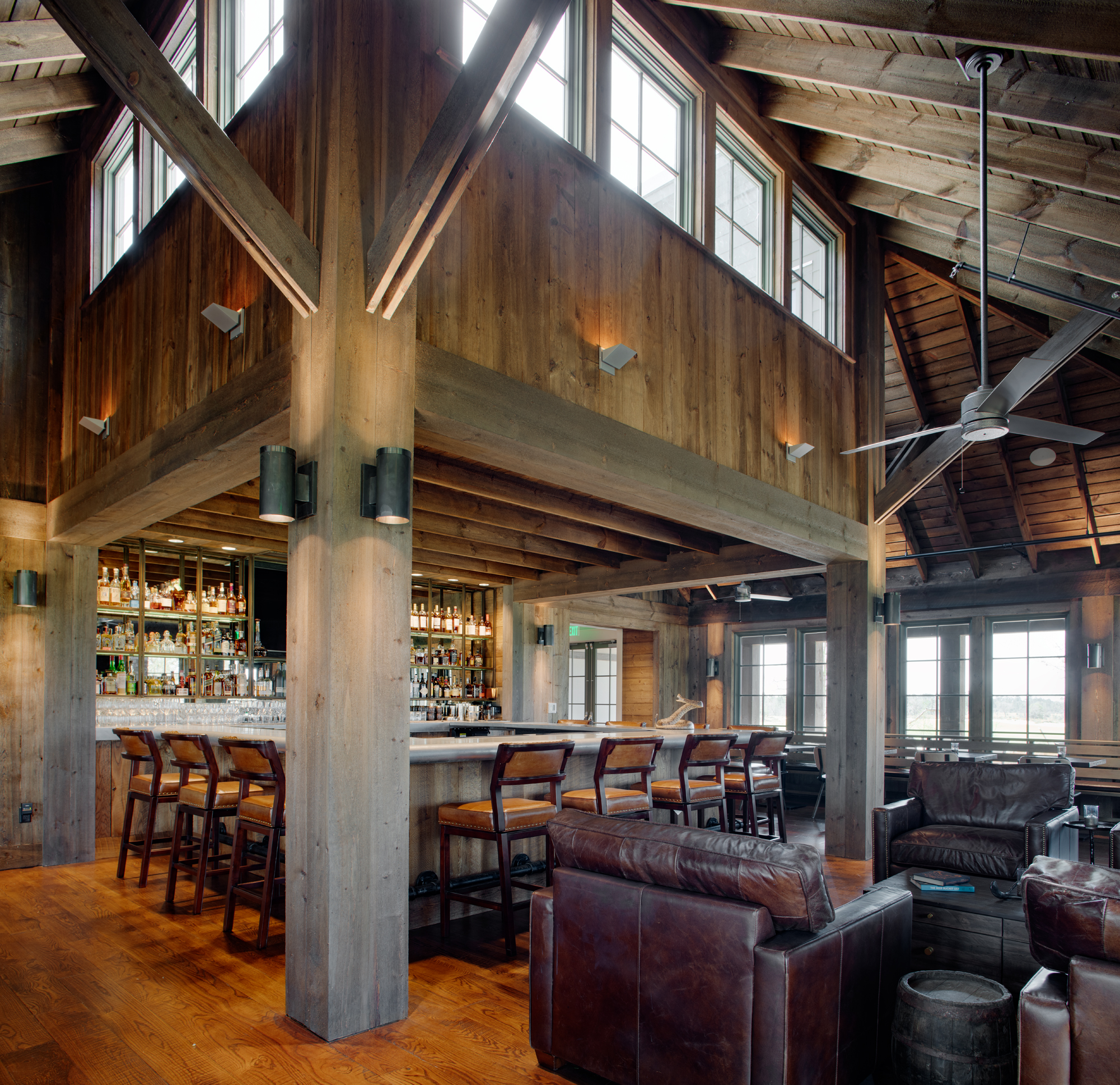 The rustic bar and gathering area at the Ohooppee Match Club is clad in reclaimed wood and features a masculine esthetic, design by J. Banks Design Group